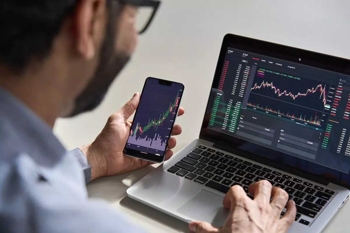 Investor checking stocks on laptop and cellphone