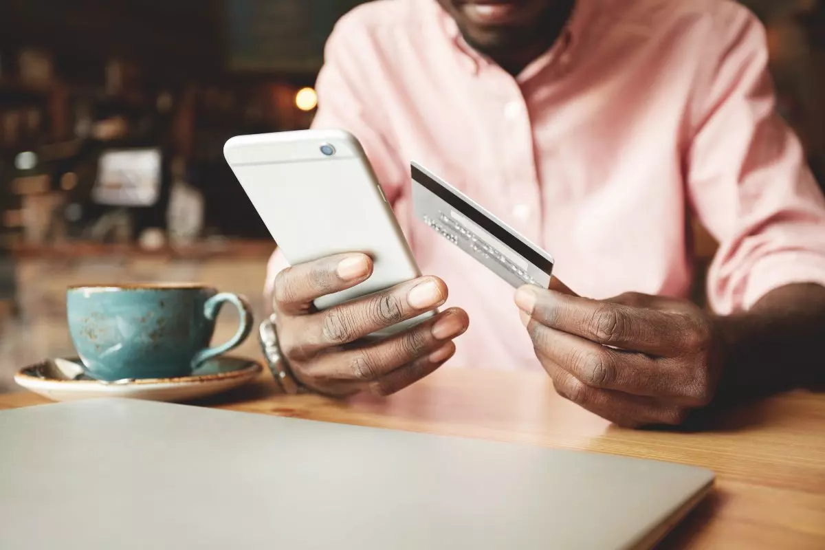 Individual using credit card to make purchase on cellphone.